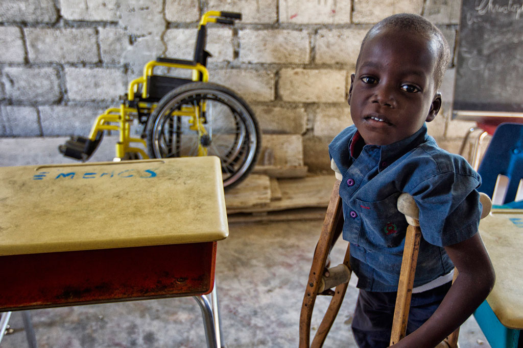 african boy with crutches and wheelchair in background