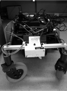 This figure shows a base of a power wheelchair with a laser attached between the castor wheels and pointing straight down to the ground.