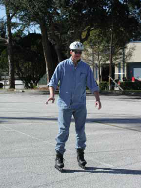Figure 1: Photo. An inline skater. A man using inline skates is skating in a parking lot.
