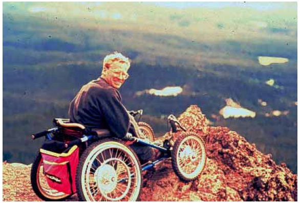 Figure 15: Photo. Another off-road racing wheelchair. A man is in an off-road racing wheelchair. He is on a cliff overlooking a valley.