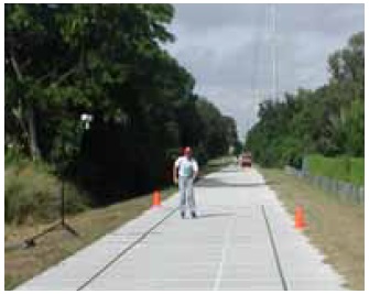 Figure 23: Photos. Equipment testing at data collection stations. This is a mosaic of five photos. 
Photo 23d: An inline skater traveling through the acceleration station. He is being filmed by a camera mounted adjacent to the trail.
