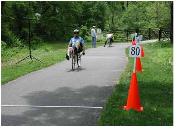 Figure 34: Photo. Participants accelerated along a 60-meter (200-foot) section of the course. A participant on a recumbent bicycle is accelerating to his normal riding speed. This section of the course is marked with transverse lines that are 12.2 meters (40 feet) apart.