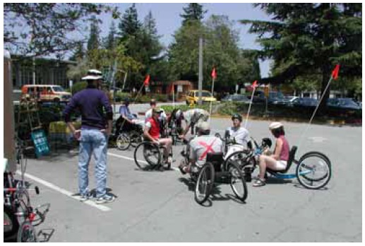 Figure 44: Photo. Thirty-two hand cyclists were active participants in this study. Three participants on hand cycles and one participant in a manual wheelchair are waiting for instructions from an event staff person.