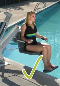 Woman sitting in and operating a pool lift to enter the pool with a green check mark at the bottom of the image, indicating an accessible element