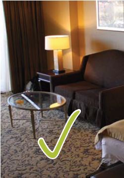 A hotel room with a couch, coffee table, and a lamp with a green check mark at the bottom of the image, indicating an accessible element