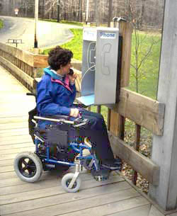 Photo of a woman using an outdoor telephone.
