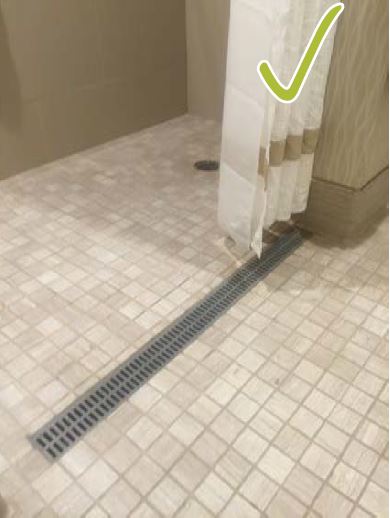 Floor drain that extends the length of the shower with a green check mark on image to indicate accessible element