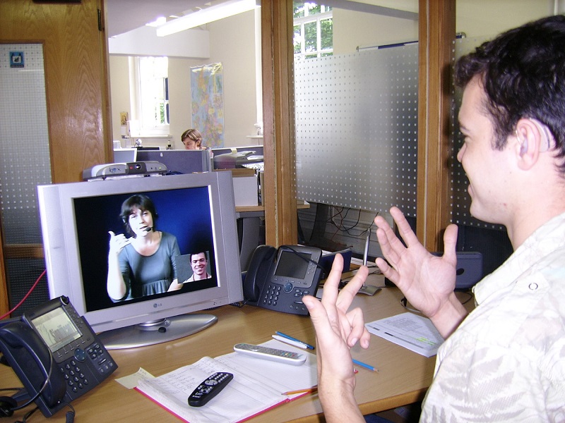 Deaf man signing to video relay communication assistant