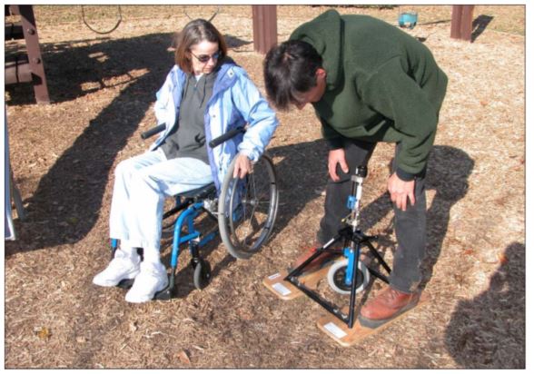 woman in wheelchair looks on as many leans over to observe the reading on a rotational penetrometer