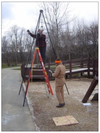 man stands on ladder holding rope while another man stands on the ground, writing on a clipboard