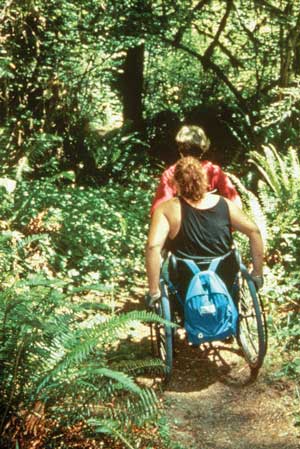 Photo of two people using wheelchairs on a trail.