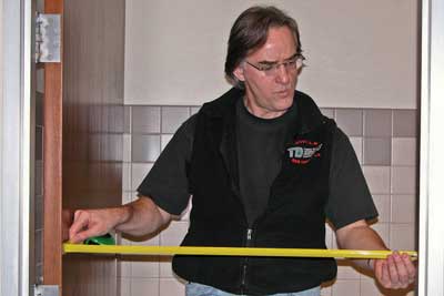 Photo of a man measuring the clear width of a doorway.