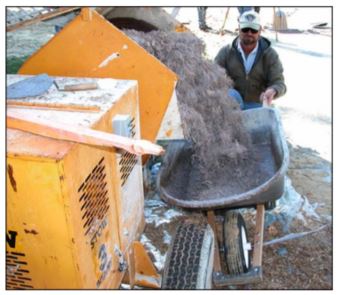 man holding wheelbarrow that is being loaded from a mortar mixing machine with binder-ewf mixture