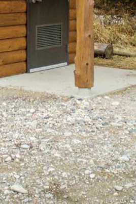 Photo showing about a one-inch vertical drop from a concrete entry porch floor to the adjacent gravel walkway. 