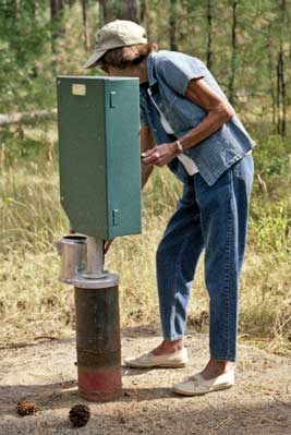 Photo of a thin, frail woman operating an accessible handpump with one hand.