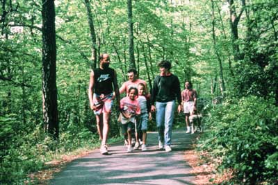Photo of four adults, two children, and a service dog walking on a paved trail.