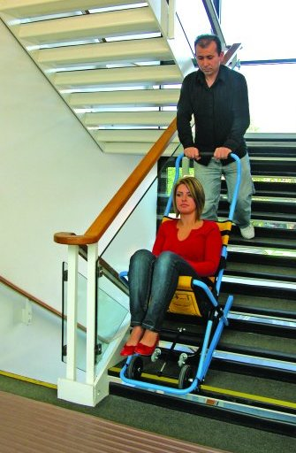 Man assisting a woman down the stairs with an "emergency stair descent device.