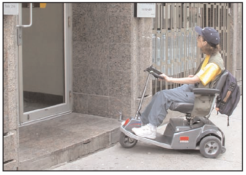 person in a motorized wheelchair at the entrance to a building