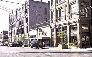 A photograph of a street scene in a downtown block. A street corner is shown with curb ramps.