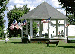 A photo of a gazebo in a public park surrounded by American flags.
