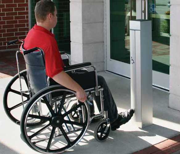 Man in manual wheelchair activates automatic door control with his foot