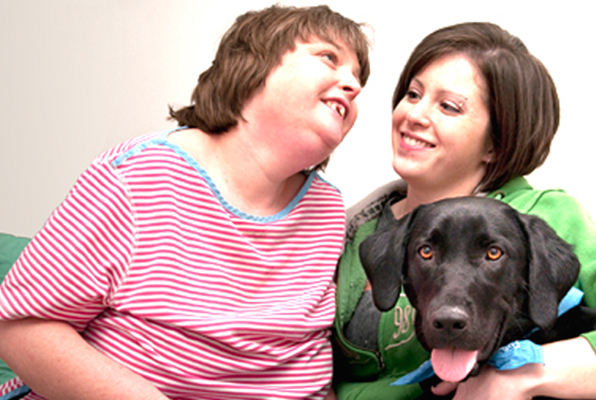 Photo showing two women and a service dog