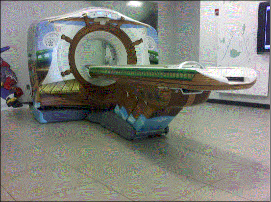 This is picture of a CT system (this one has decals on it for use in a children’s hospital). It is also representative of a MR table. The table on this particular model is 7+ ft long, about 24 inches wide, and has a minimum height of about 18 inches. Note the emergency extraction handle at the foot end of the table. Also note that there is not structural material under the table side covers where transfer supports could sufficiently be anchored.