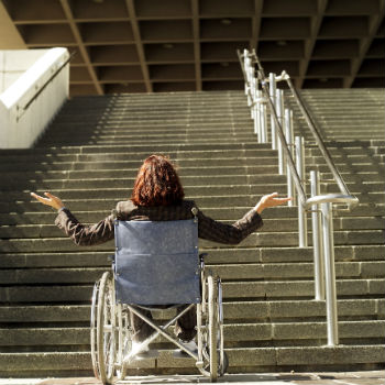 photo of a woman in a wheelchair facing stairs