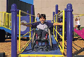 photo of boy using a wheelchair descending ramp with handrails on both sides